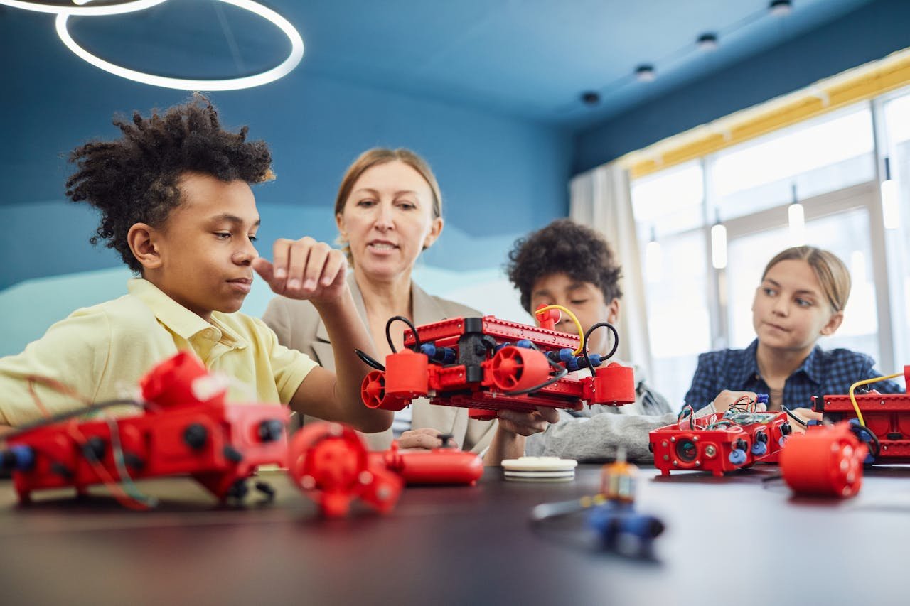 about-us-01 Young students and teacher collaborating on a robotics project in a classroom setting.